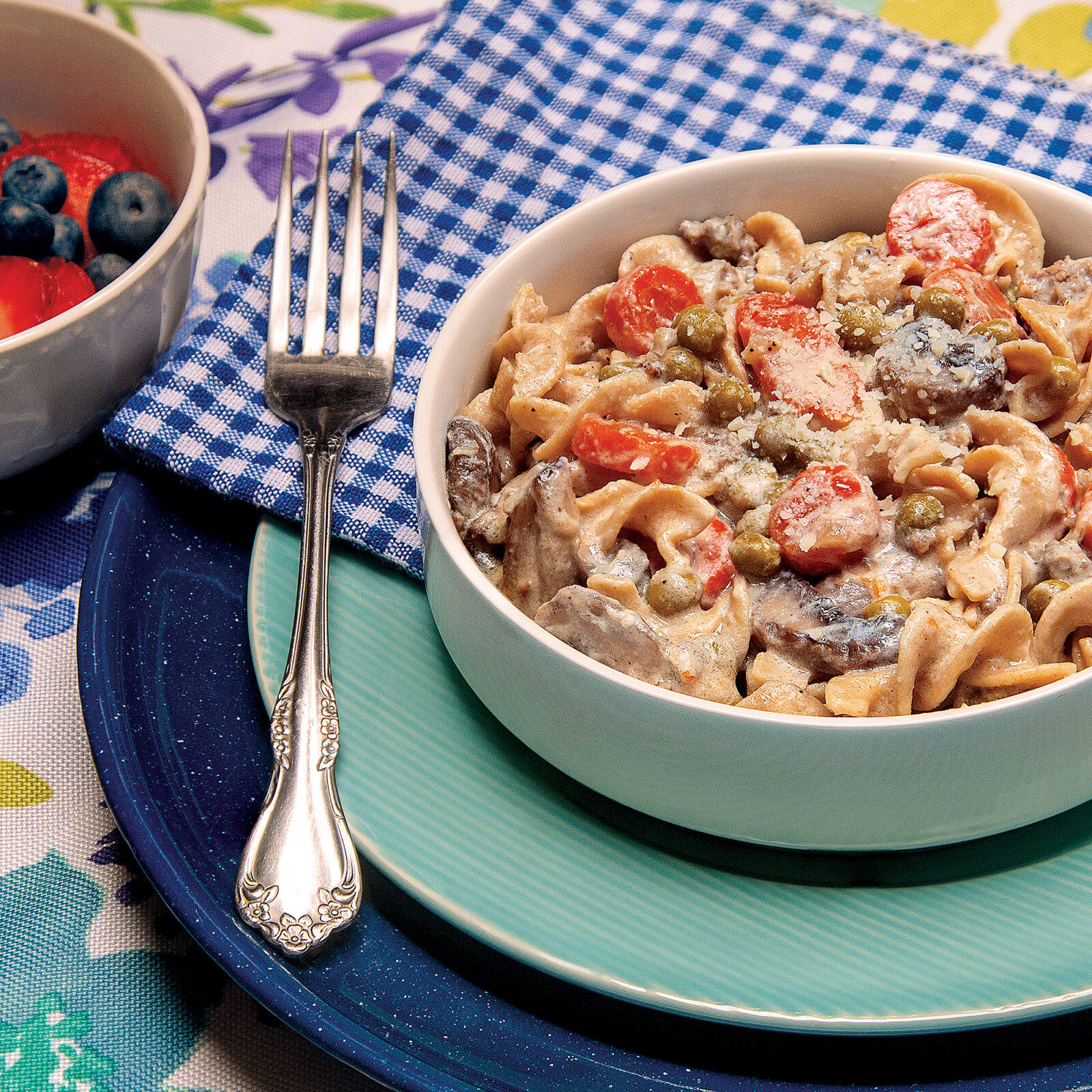 bowl of beef stroganoff with noodles, peas, carrots and mushrooms